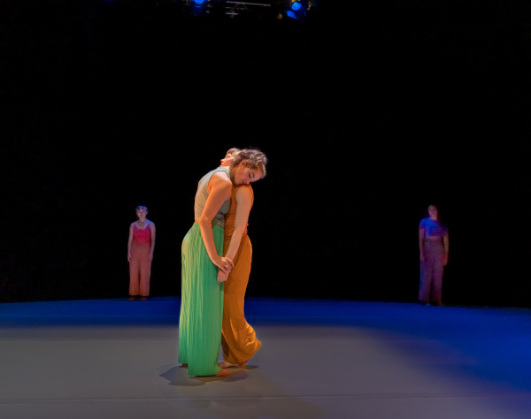 Two dancers connect with heads on each other's shoulders.