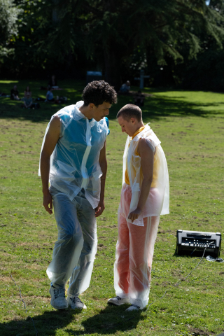 Two dancers in translucent plastic vests and pants.