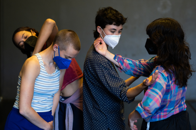 Four dancers pose in close proximity, connecting with arms.