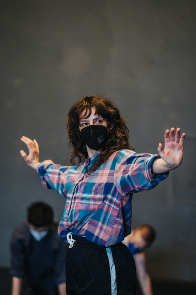 A dancer is captured with arms out to their side, hands flexed up.